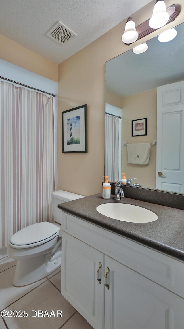 bathroom with a textured ceiling, tile patterned flooring, vanity, and toilet