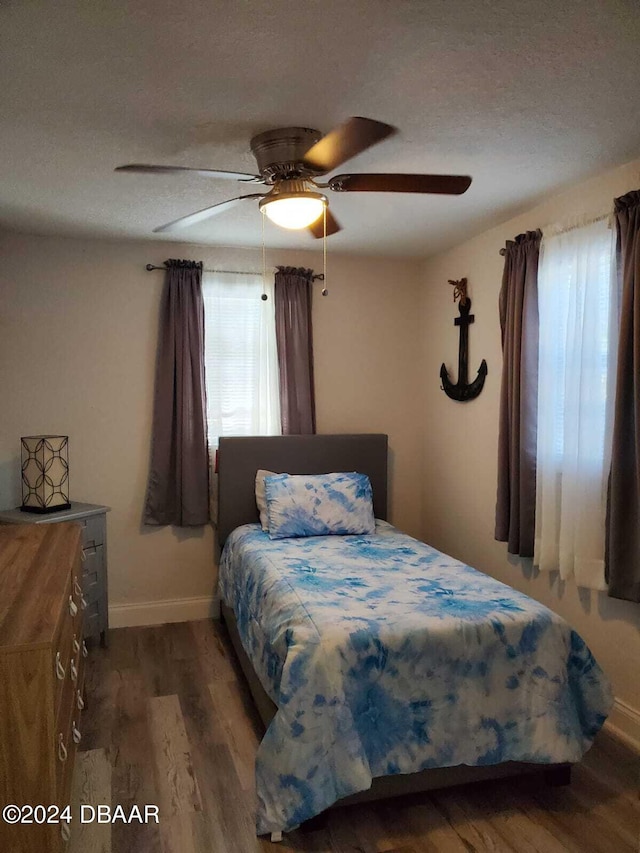 bedroom with ceiling fan, a textured ceiling, and hardwood / wood-style flooring