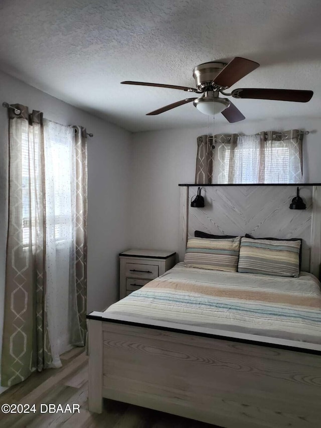 unfurnished bedroom with ceiling fan, wood-type flooring, and a textured ceiling