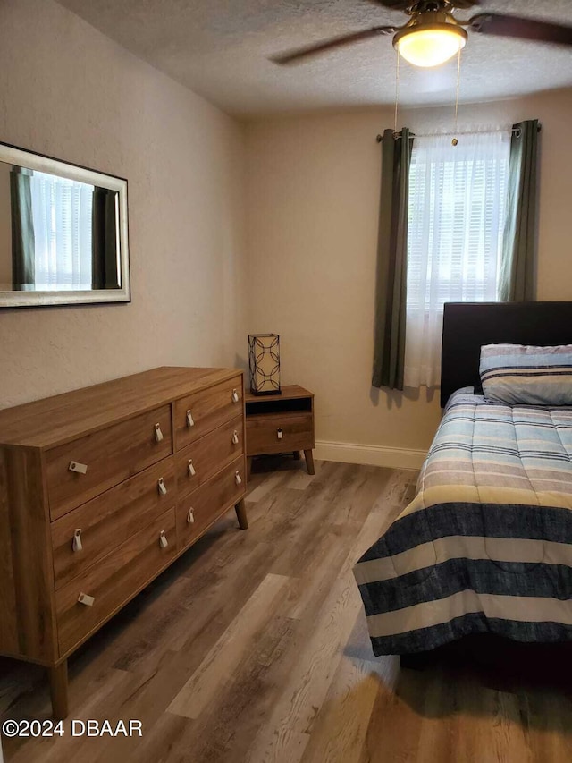 bedroom with ceiling fan, light hardwood / wood-style floors, and a textured ceiling