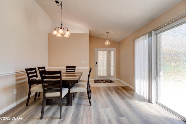 dining room with an inviting chandelier, light wood-style flooring, baseboards, and vaulted ceiling