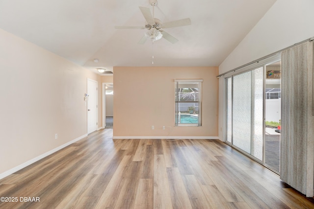 empty room featuring ceiling fan, light wood-style flooring, baseboards, and vaulted ceiling