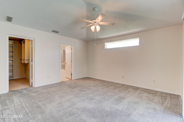 unfurnished bedroom featuring carpet floors, a walk in closet, visible vents, and baseboards