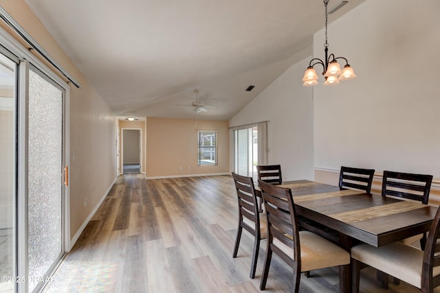 dining area featuring lofted ceiling, light wood-style flooring, ceiling fan with notable chandelier, visible vents, and baseboards