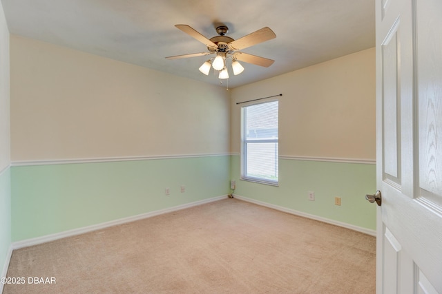 carpeted empty room with a ceiling fan and baseboards