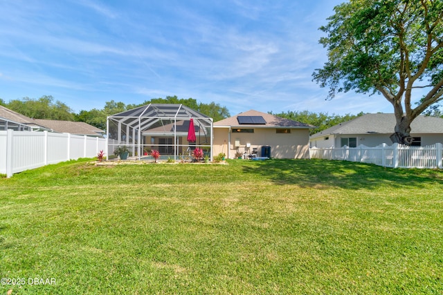 back of property with a fenced backyard, a patio area, a lanai, and a lawn