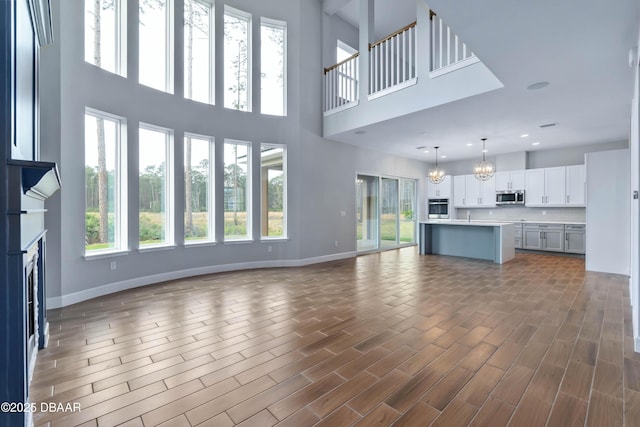 unfurnished living room with a chandelier, a healthy amount of sunlight, a high ceiling, and sink