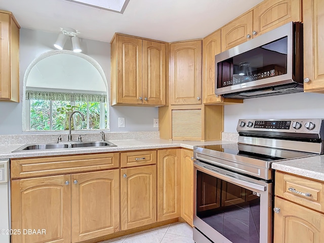 kitchen featuring light tile patterned floors, light brown cabinets, stainless steel appliances, a sink, and light countertops