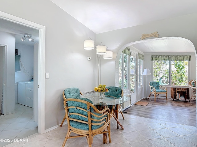 dining room with electric panel, arched walkways, vaulted ceiling, washing machine and dryer, and light tile patterned flooring