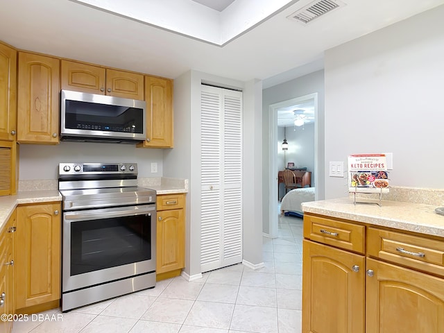 kitchen with light tile patterned floors, visible vents, baseboards, appliances with stainless steel finishes, and light countertops