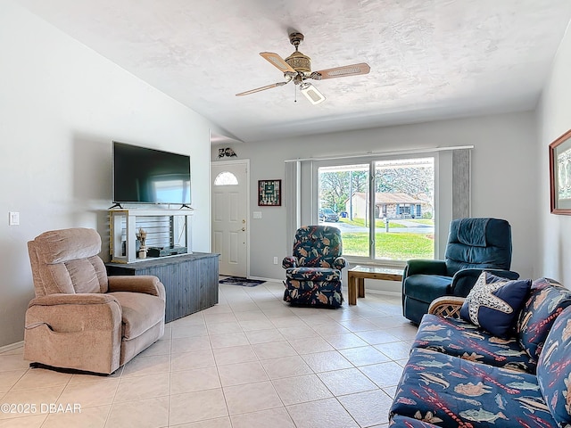 living area featuring light tile patterned floors, ceiling fan, baseboards, and a textured ceiling