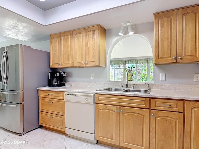 kitchen featuring light tile patterned floors, stainless steel fridge, white dishwasher, light countertops, and a sink