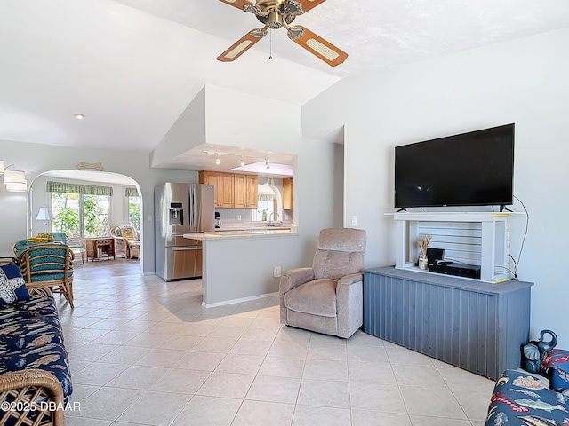 living area with light tile patterned floors, baseboards, arched walkways, a ceiling fan, and lofted ceiling