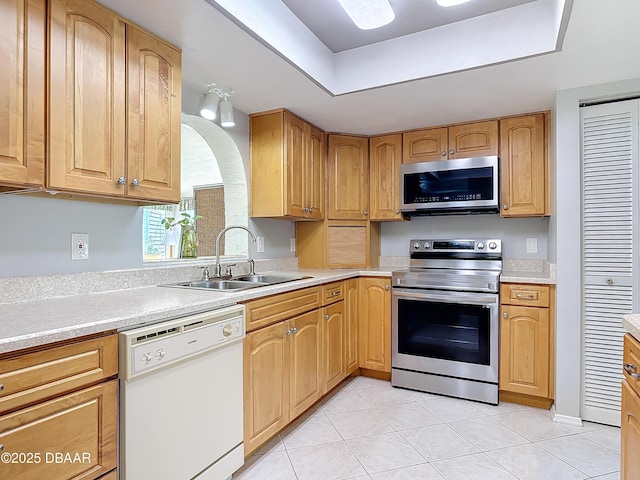 kitchen featuring a raised ceiling, appliances with stainless steel finishes, light countertops, a sink, and light tile patterned flooring