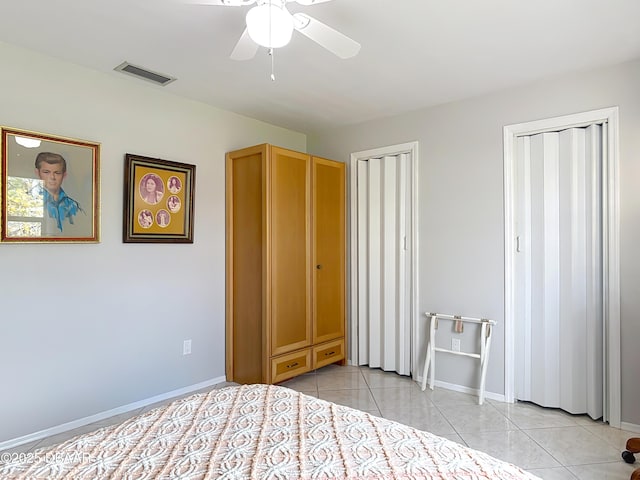 unfurnished bedroom with visible vents, two closets, baseboards, and light tile patterned floors