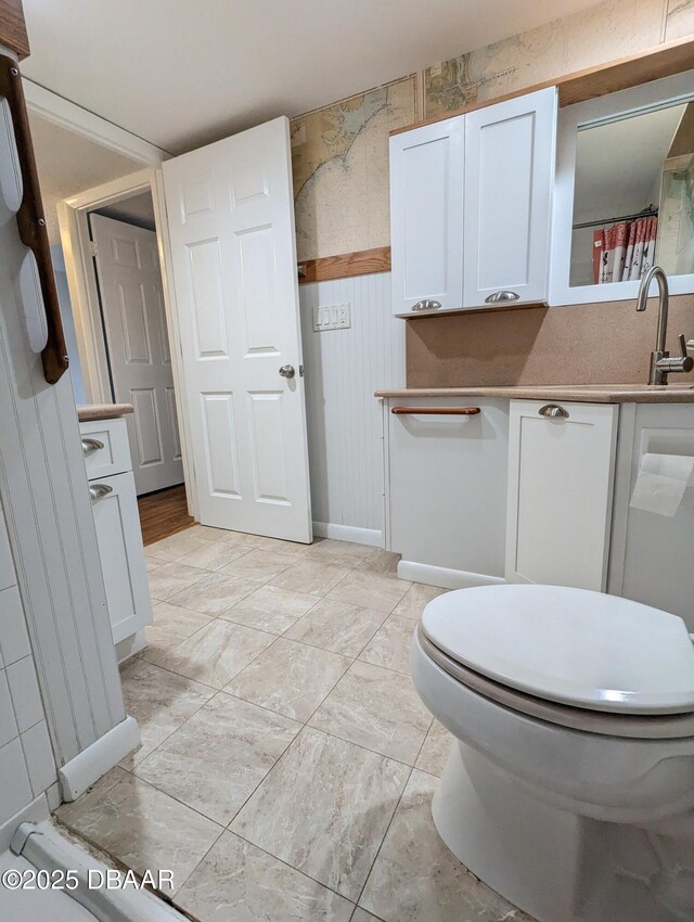 717 S Beach St Unit 102C, Daytona Beach, FL 32114 - bathroom with vanity, wainscoting, and curtained shower