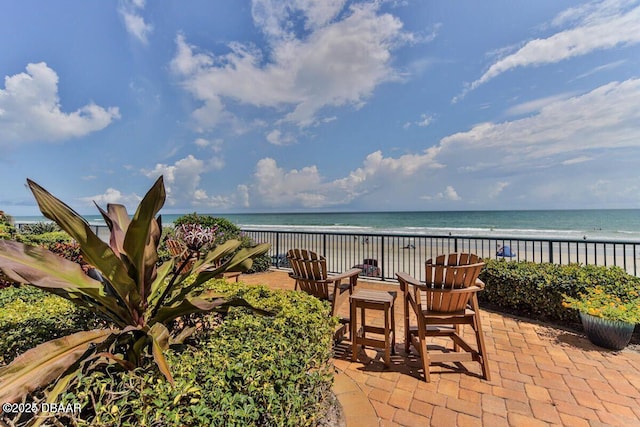 view of patio featuring a water view and a beach view