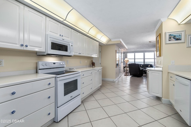 kitchen with light tile patterned floors, white appliances, white cabinets, light countertops, and ornamental molding