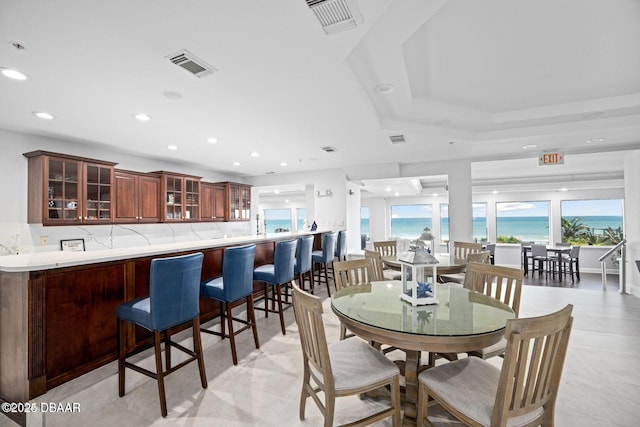 dining space featuring a water view, visible vents, and recessed lighting