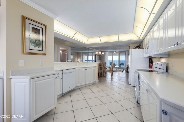 kitchen with a chandelier, a peninsula, white appliances, white cabinetry, and light countertops