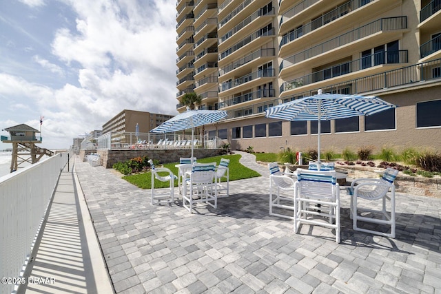 view of property's community with outdoor dining space, a patio area, and fence