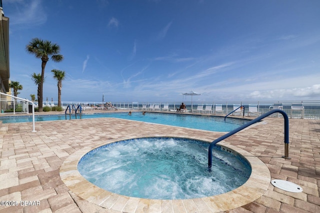 pool with a water view, a patio area, and a hot tub