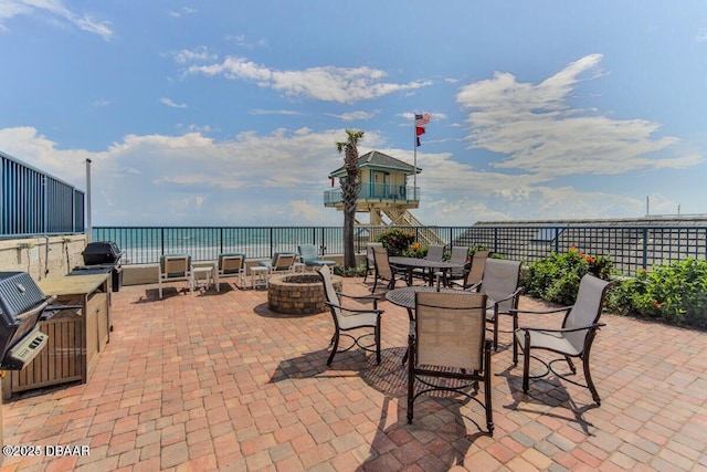 view of patio with a fire pit, outdoor dining space, grilling area, and a water view