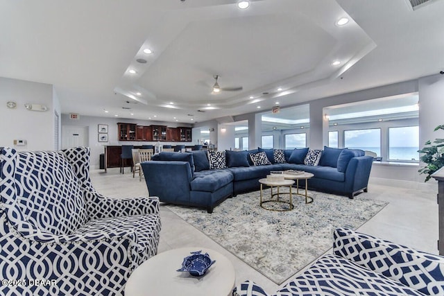 living room with a ceiling fan, recessed lighting, a raised ceiling, and baseboards