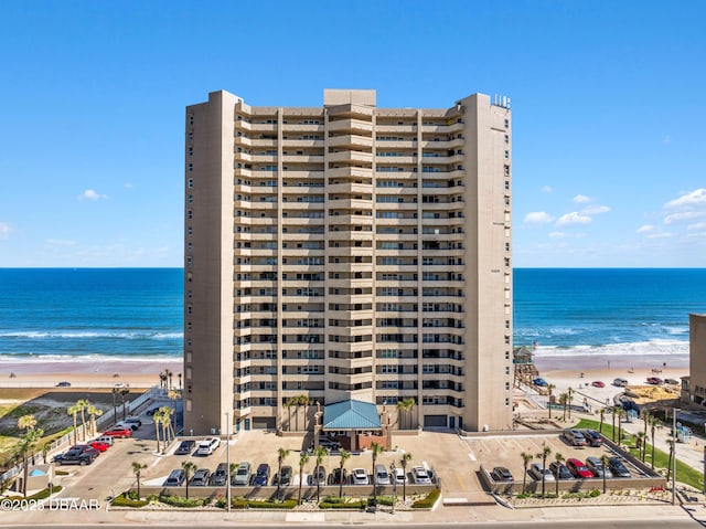 view of building exterior with a water view and a beach view