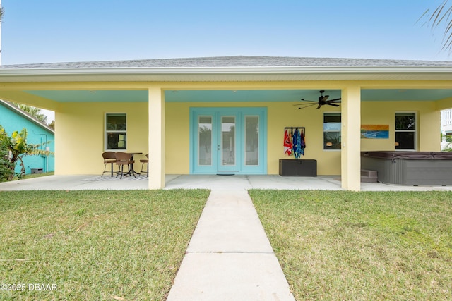 rear view of property with a patio, a yard, ceiling fan, and a hot tub