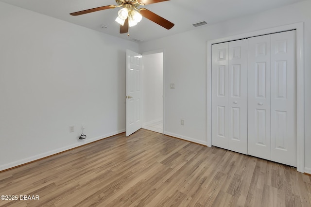 unfurnished bedroom featuring baseboards, visible vents, light wood finished floors, ceiling fan, and a closet