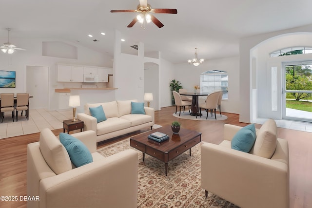 living area featuring light wood-type flooring, visible vents, high vaulted ceiling, ceiling fan with notable chandelier, and recessed lighting