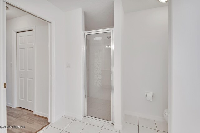 full bath with tile patterned floors, baseboards, toilet, and a stall shower