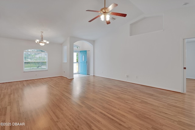 spare room featuring baseboards, high vaulted ceiling, arched walkways, light wood-style floors, and ceiling fan with notable chandelier