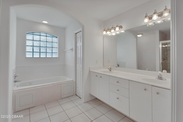 full bath featuring tile patterned floors, double vanity, a garden tub, and a sink