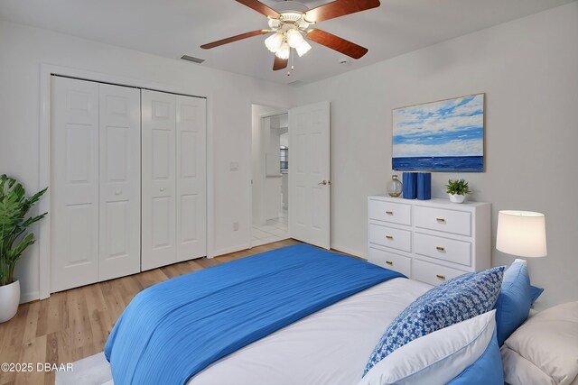 bedroom with visible vents, a ceiling fan, a closet, light wood-style floors, and baseboards