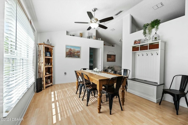 dining area featuring ceiling fan, high vaulted ceiling, a textured ceiling, and light wood-type flooring