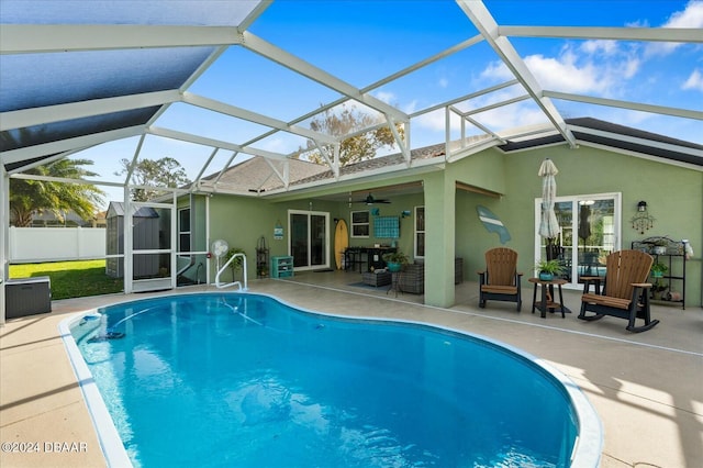 view of swimming pool with glass enclosure, ceiling fan, and a patio