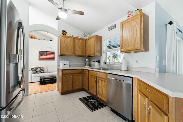 kitchen featuring sink, vaulted ceiling, light tile patterned floors, appliances with stainless steel finishes, and kitchen peninsula