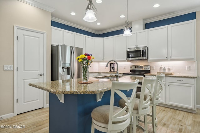 kitchen featuring light stone counters, a center island with sink, white cabinetry, light wood-type flooring, and appliances with stainless steel finishes