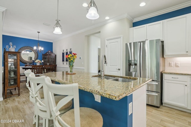 kitchen with sink, stainless steel refrigerator with ice dispenser, a kitchen island with sink, white cabinets, and light wood-type flooring