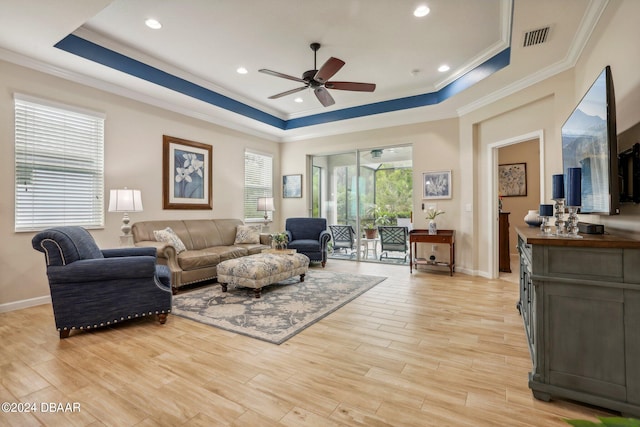 living room with ceiling fan, a raised ceiling, light hardwood / wood-style flooring, and ornamental molding