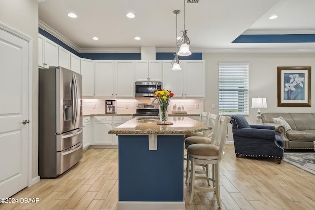 kitchen featuring white cabinetry, light stone counters, appliances with stainless steel finishes, light hardwood / wood-style flooring, and a kitchen island