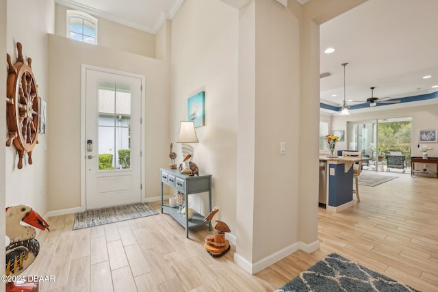 entryway with ornamental molding, ceiling fan, and light hardwood / wood-style floors