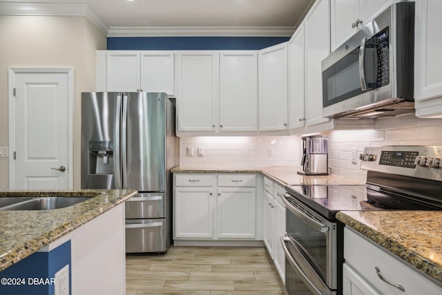 kitchen featuring white cabinetry, light stone counters, tasteful backsplash, appliances with stainless steel finishes, and ornamental molding