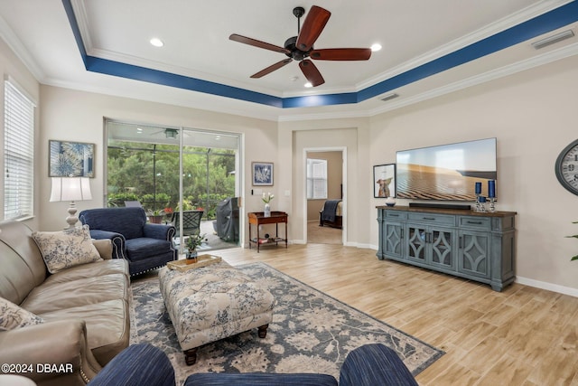 living room featuring a tray ceiling, light hardwood / wood-style floors, and crown molding