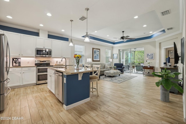 kitchen with stainless steel appliances, dark stone counters, sink, a kitchen island with sink, and pendant lighting