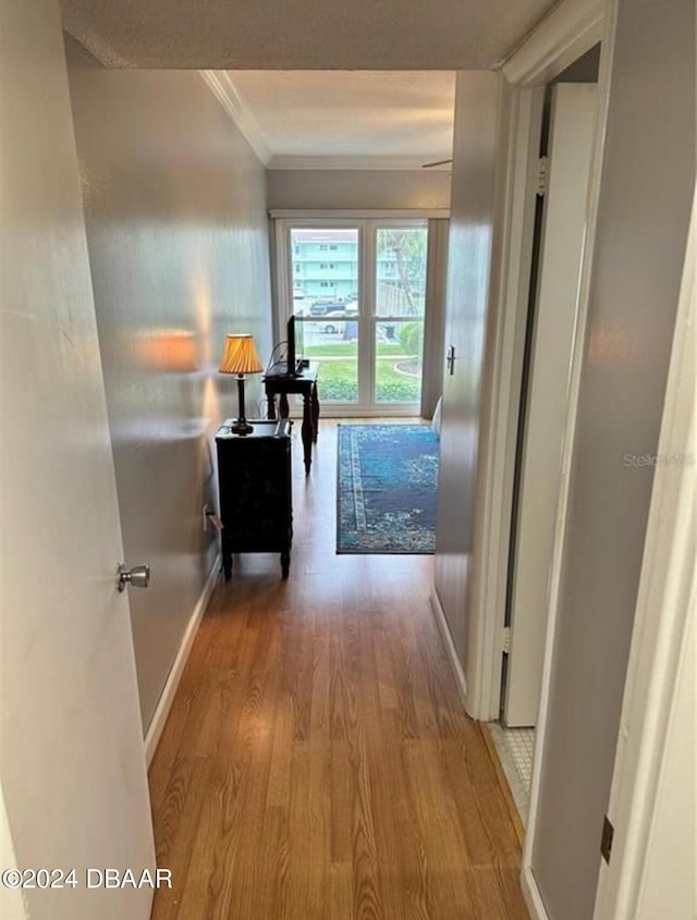 corridor with light hardwood / wood-style flooring and crown molding