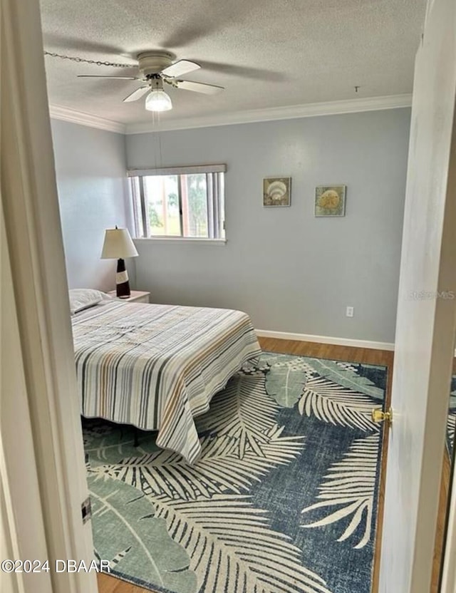 bedroom featuring a textured ceiling, hardwood / wood-style flooring, ceiling fan, and crown molding