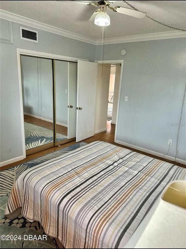 bedroom with ceiling fan, a closet, wood-type flooring, and ornamental molding